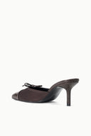 Espresso mule with snake-texture upper, lace front, and narrow stiletto heel.