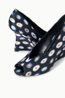 Angled view of peep-toe wedge heel shoes with floral pattern fabric