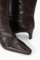 Close-up of dark espresso brown snake-embossed knee boot toe and low heel.