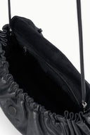 Black convertible bag close-up showing inner zip pocket and ruched edge