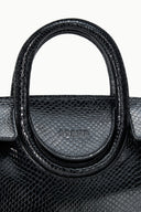 Maude mini carryall bag close-up: curved handle on dark textured leather