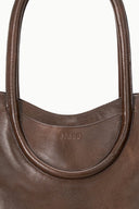 MAUDE espresso tote bag close-up of curved front pocket and 'STAUD' logo