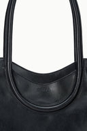 MAUDE black north-south tote, close-up of curved handle opening with embossed logo