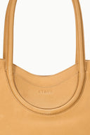 Tan tote with curved neckline and embossed brand mark at the handle base