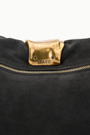Dark mocha cuff clutch close-up: gold-tone clasp with logo and snap buttons