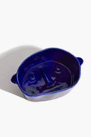 Small ceramic dog bowl, glossy blue with dog-face embossing and side rim