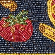 Close-up beaded motif with red fruit and green leaf on dark navy background
