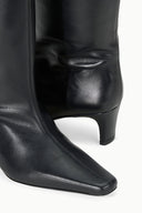 Mid-calf black leather boot with pointed toe and low block heel