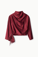 Burgundy silk draped top with cowl neck, 3/4 sleeves, and tie-bow hem detail