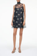 Dark sleeveless mini dress with high neck and sheer mesh layer, botanical print