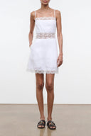 White linen mini dress with lace-trim straps and scalloped hem