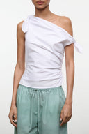 White one-shoulder wrap top with draped fabric and tied bow shoulder