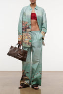 Light teal button-up shirt with long sleeves and colorful resort print accents on cuffs